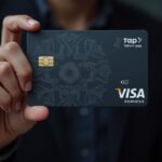 Un usuario sostiene una tarjeta cripto vinculada a una billetera sin custodia, con rendimiento en cadena y los iconos de Visa de pago con un toque.